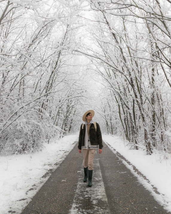 a woman in a brown hat standing on a road