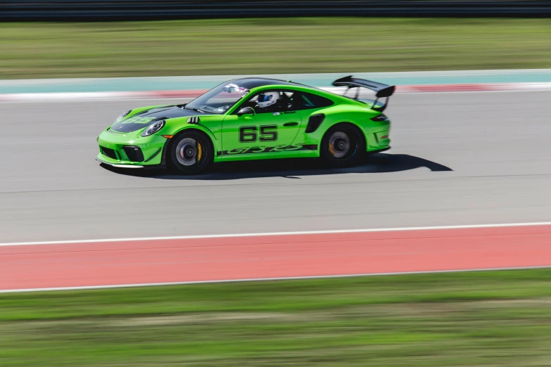 a green race car going around a turn on the track