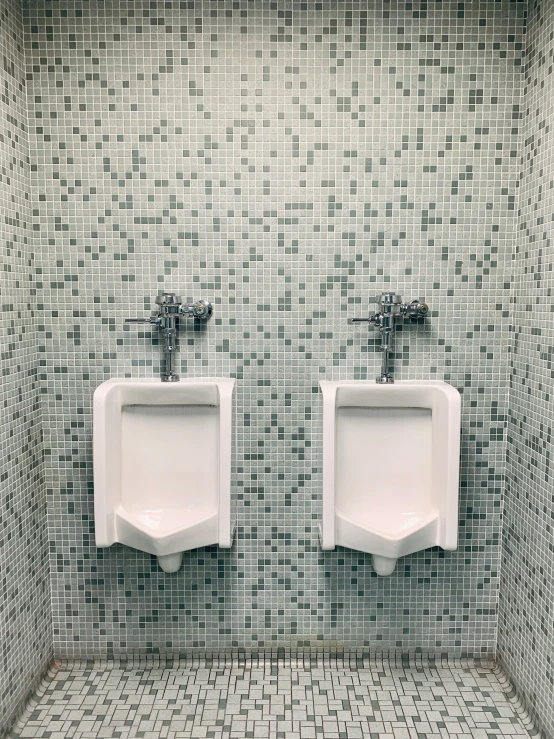 two urinals sit side by side in a tile bathroom
