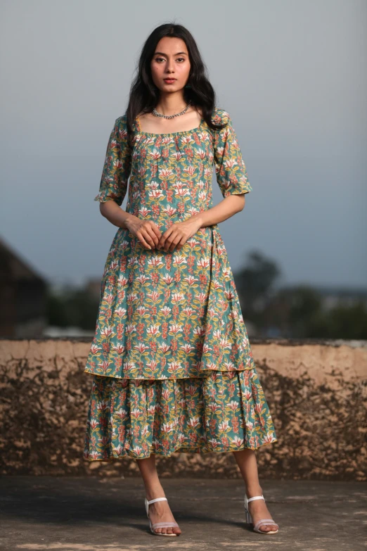 a young woman in a colorful dress with heels standing on the wall