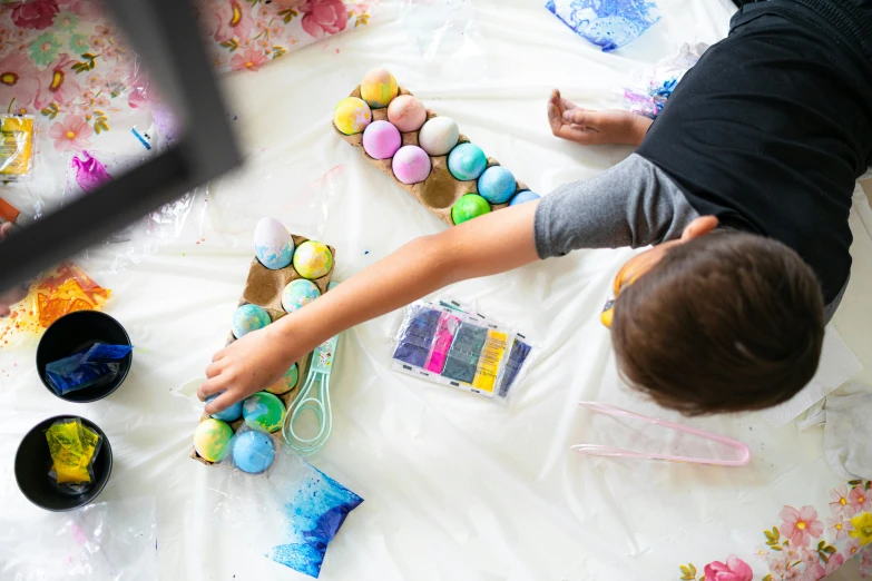 a little boy painting decorated eggs with markers and brushes