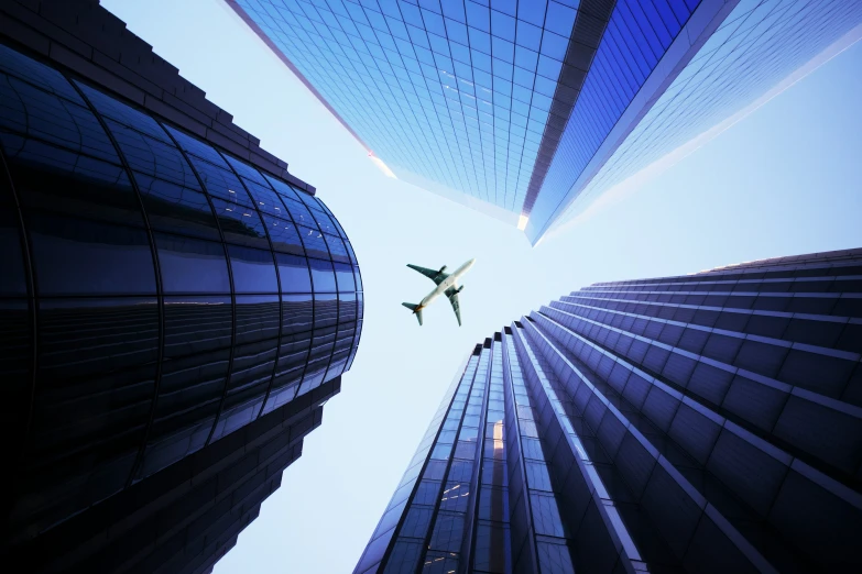 a large airplane flying through the air between buildings