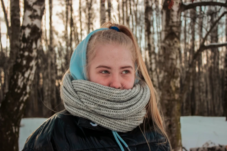 a woman is standing with her eyes closed with her head tucked into a scarf