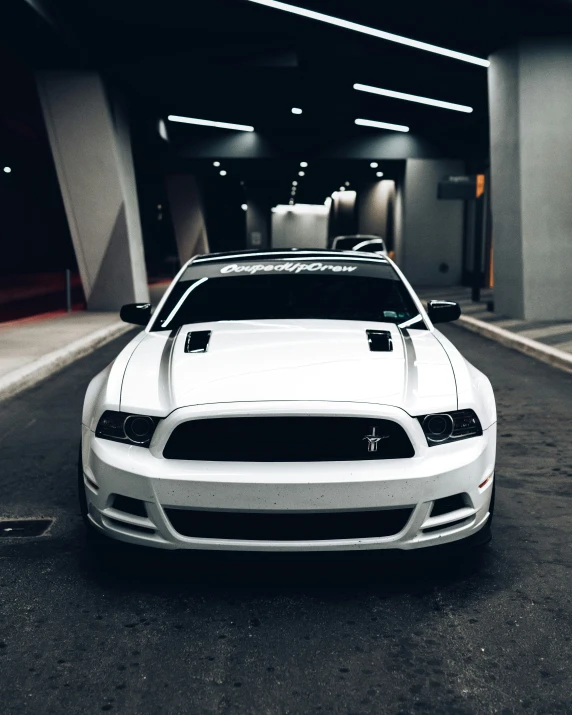 white mustang in parking garage with the hood up