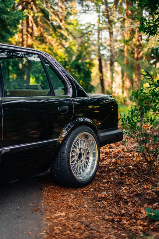 a black car parked on the side of a forest road