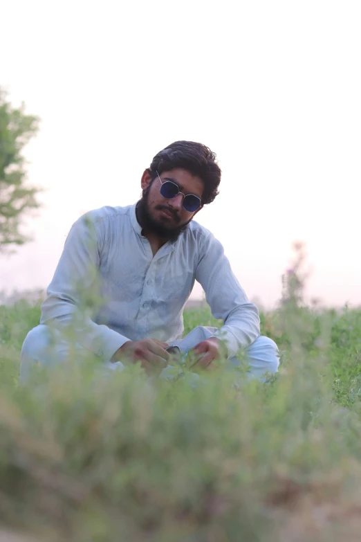 a man wearing a white shirt is sitting in the grass