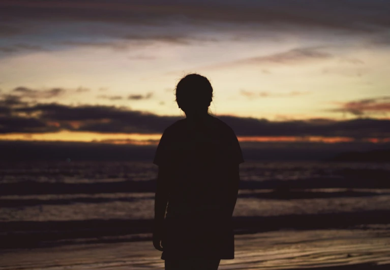 the silhouette of a man is standing in front of an ocean