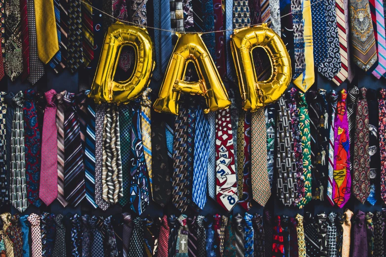 a bunch of neck ties hang next to balloons that read dad