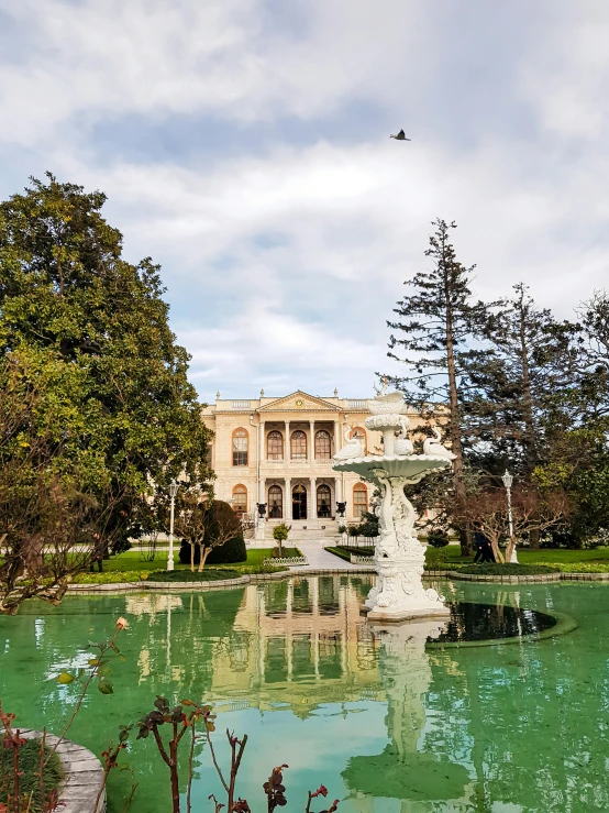 a fancy mansion is in the background in the midst of a pond