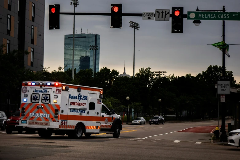 an ambulance driving across a city intersection at sunset