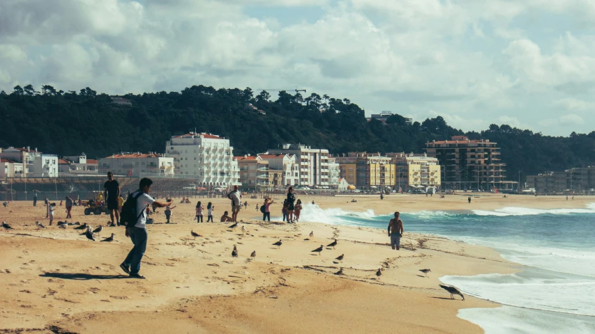 a group of people standing on top of a beach next to the ocean