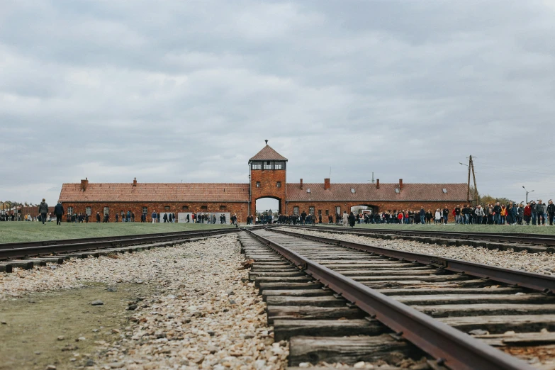 several people are gathered near a building on train tracks