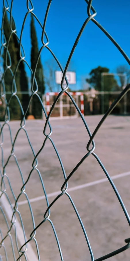 a basketball court seen through a fence in a parking lot
