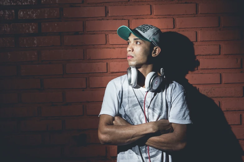 a young man is standing in front of a brick wall and headphones on