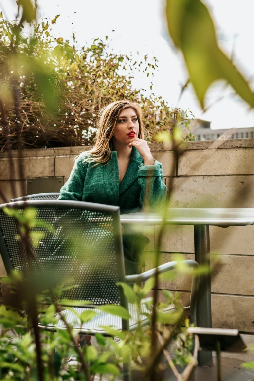 a woman sitting on the back of an outdoor chair in a courtyard