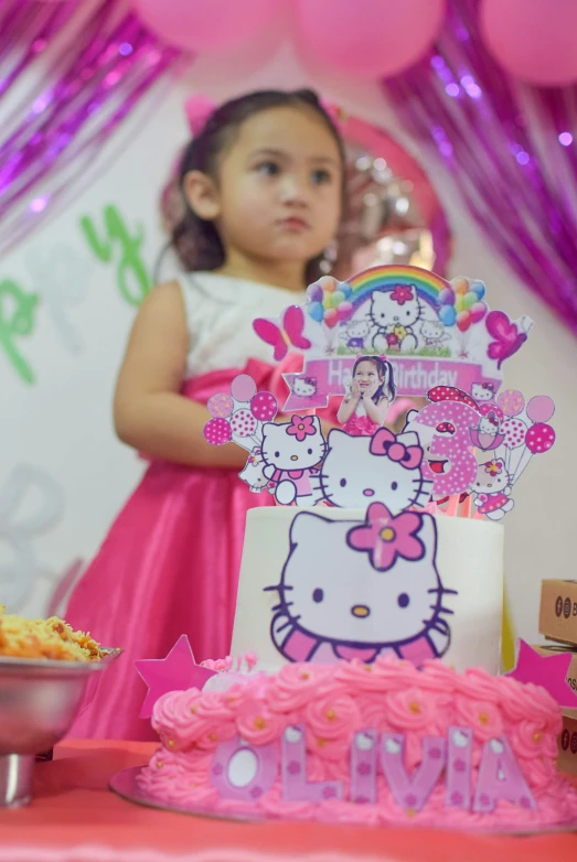 girl in pink dress at table with hello kitty cake