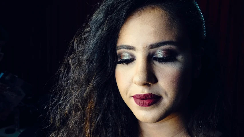 a beautiful woman with black makeup wearing a red and silver make up