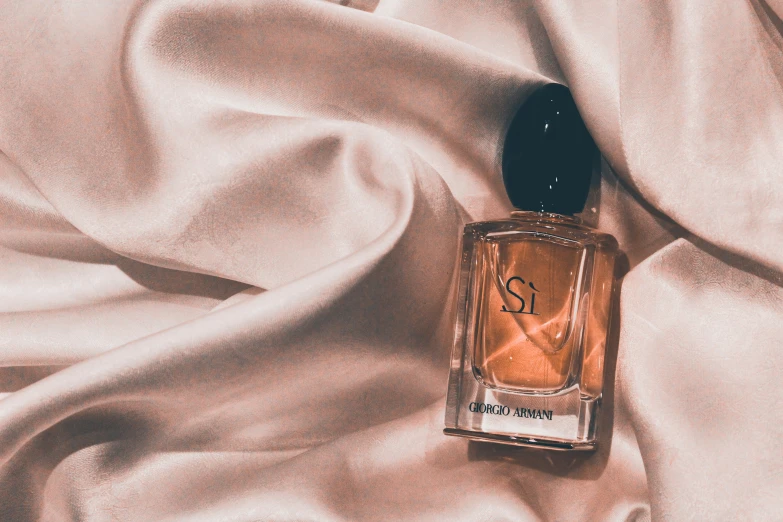 a bottle of perfume sitting on top of a satin cloth
