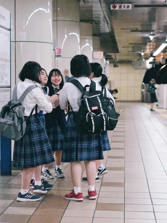 some girls in plaid skirts are standing near a sign