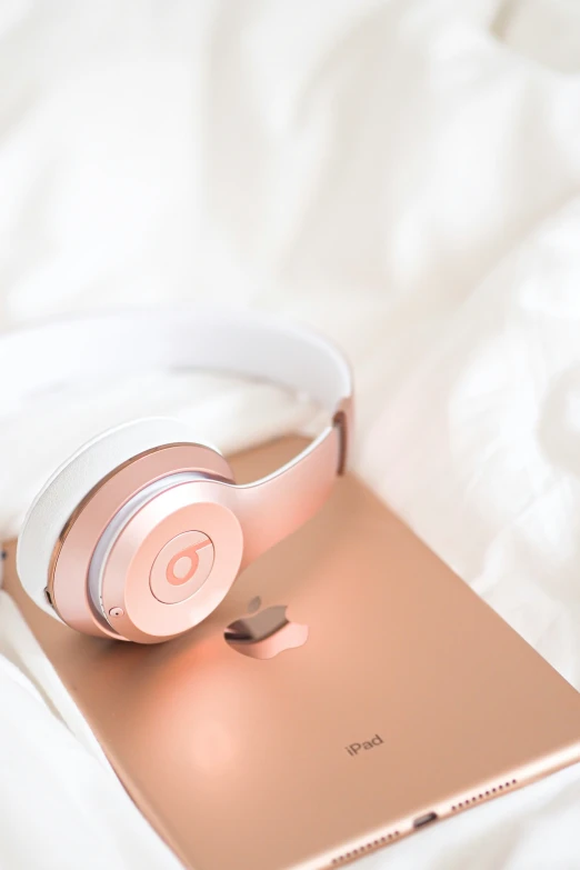 an apple mac laptop and headphones laying on a bed