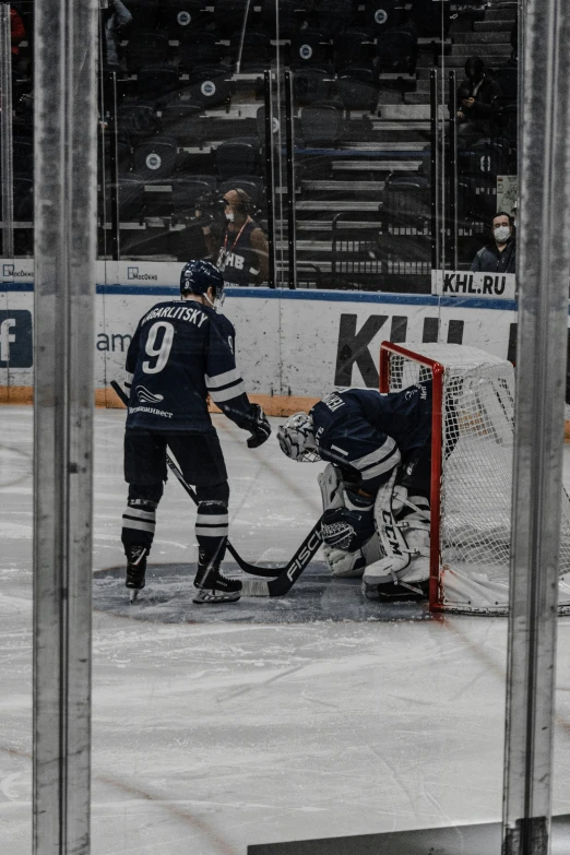 a hockey game between two teams with referee and a goalie