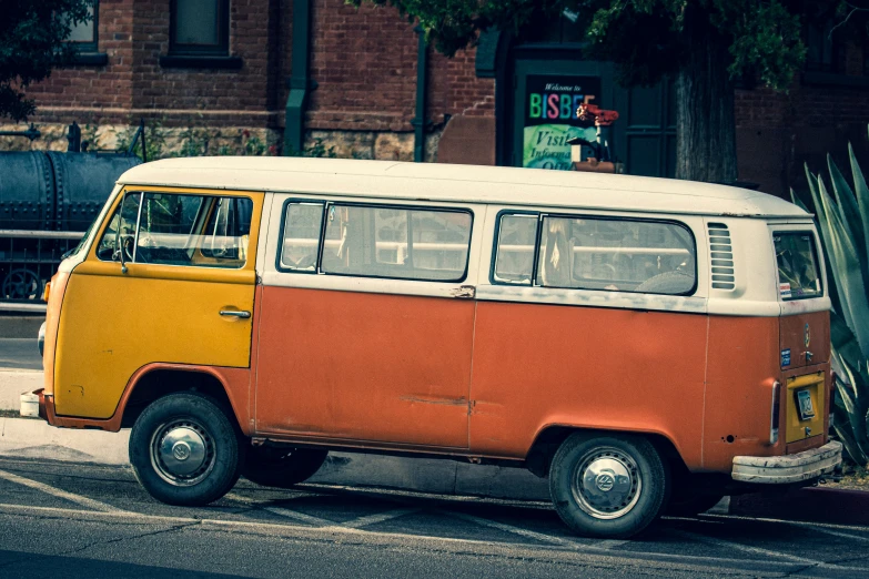 a yellow and orange van on street next to building