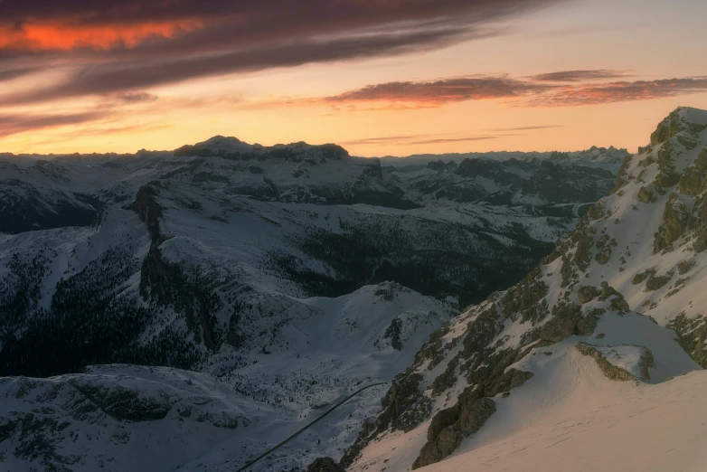 the sun is setting over the mountains, while looking at the snow covered mountain