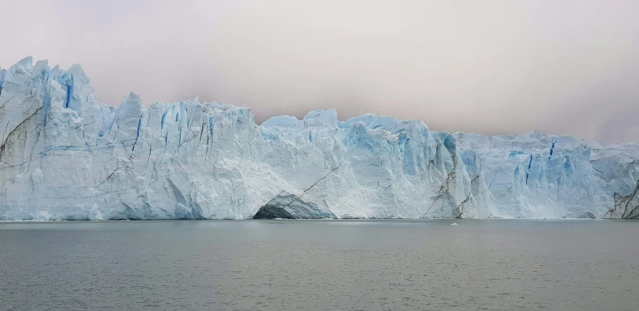 a giant blue iceberg on the water next to a body of water