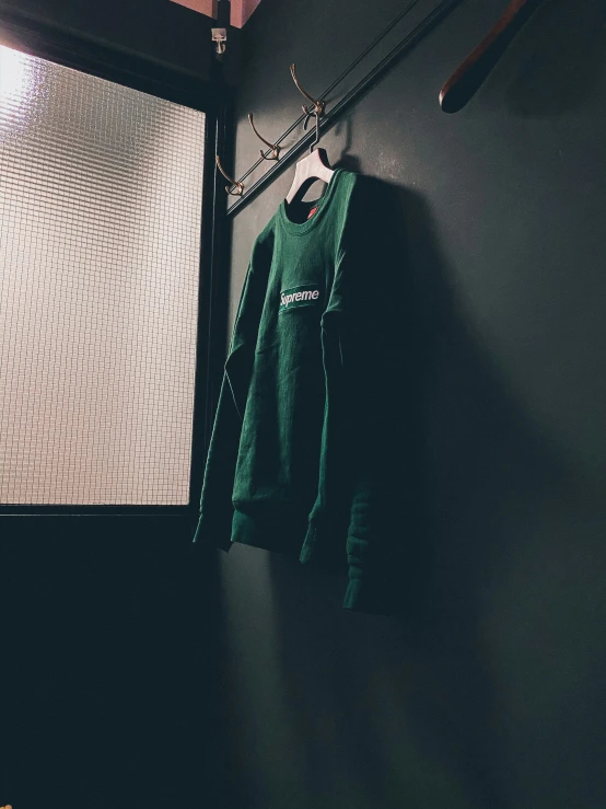 a green t - shirt on a rack hanging in front of a door