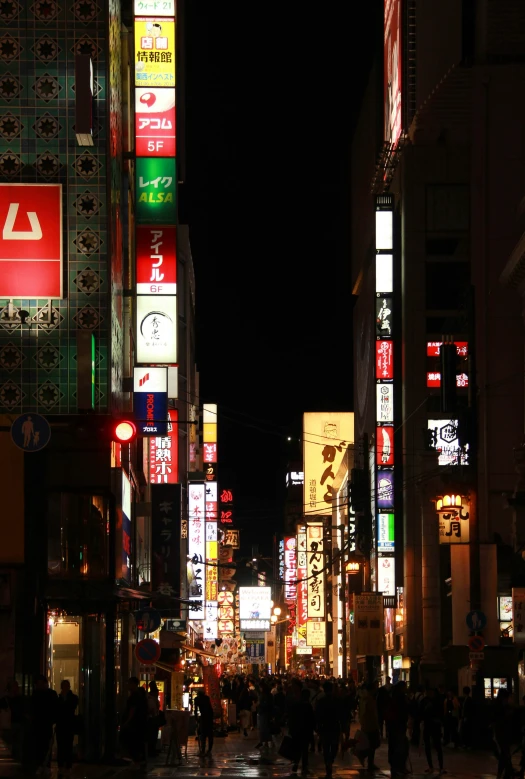 a crowded street at night with illuminated buildings in the city