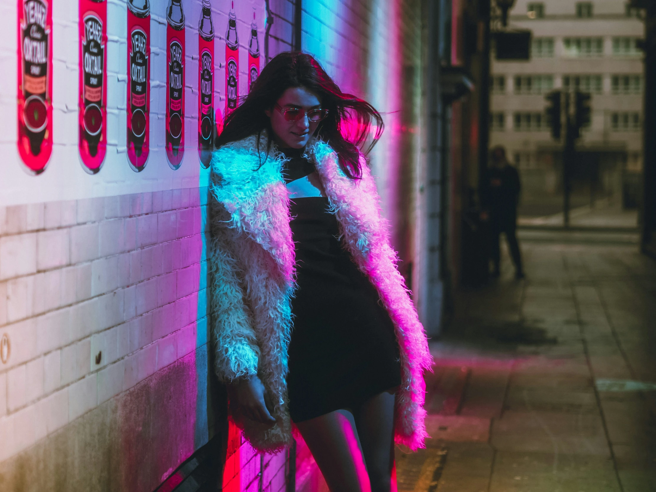 a beautiful young lady leaning against the side of a building