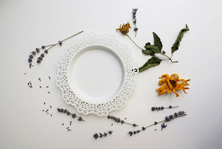 there is a white doily and some dried flowers on the table