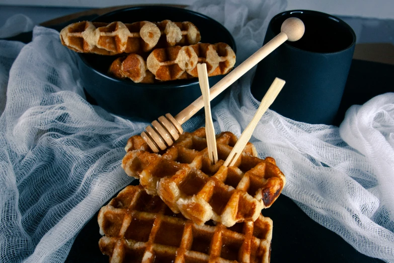 a waffle on a plate with honey sticks sticking out of it