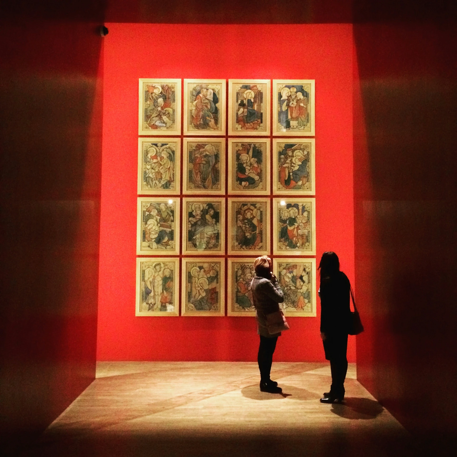 two people stand at a room with art on the walls