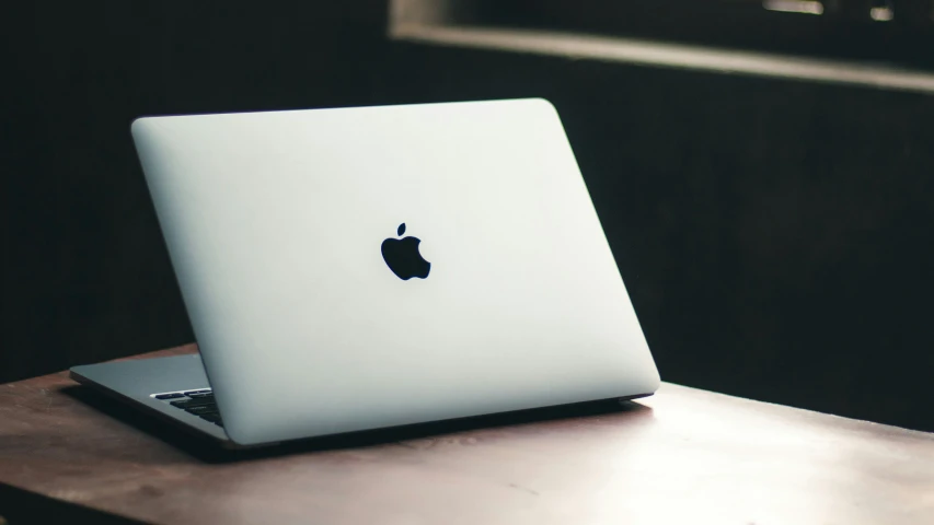 a mac laptop sitting on a desk, with its back to the camera