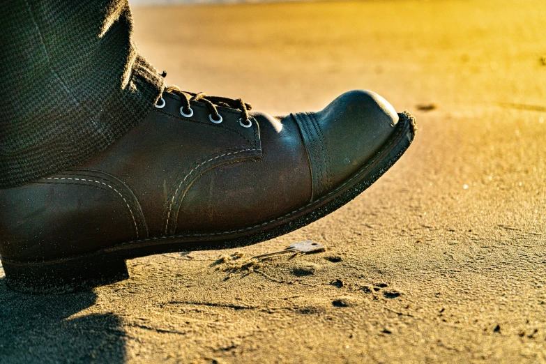 a man's feet in blue jeans and gray shoes on the ground