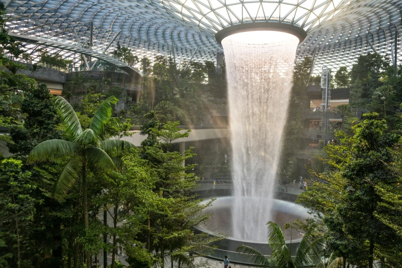 a waterfall falling over the ground in a lush green park