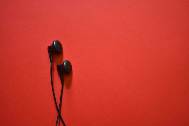 two black headphones lie on a red surface