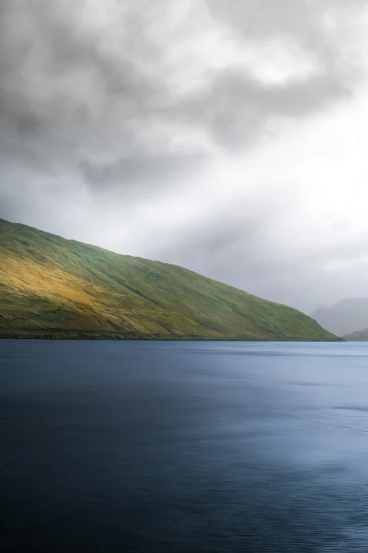 some clouds rolling over a mountain on a lake