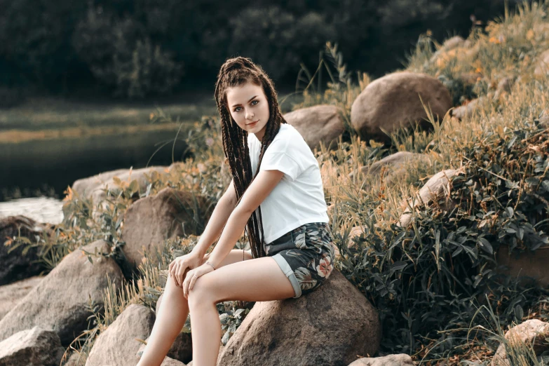 young woman sitting on rocks near stream with water