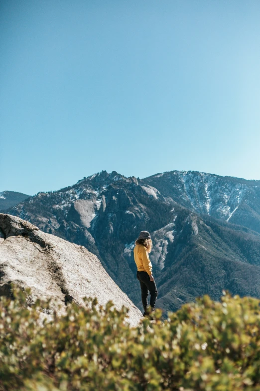 a person standing on the top of a hill with a snow covered mountain in the background