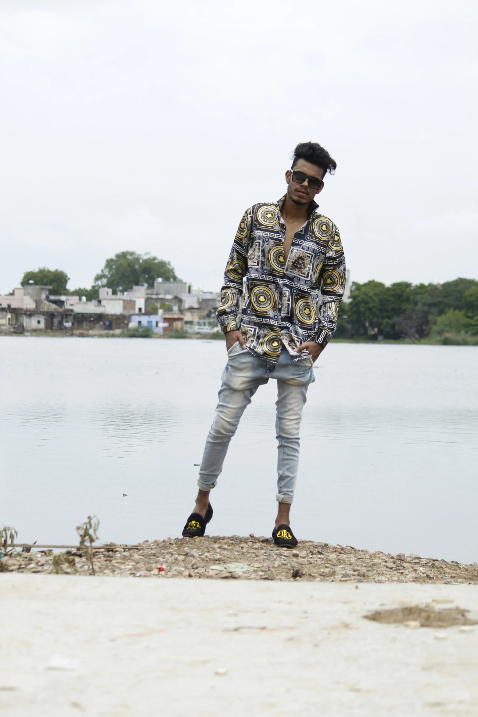 a man standing next to the water with his legs crossed