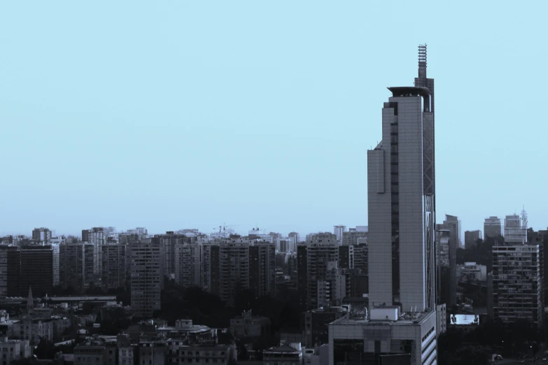 a tall building with a massive spire in front of a city skyline