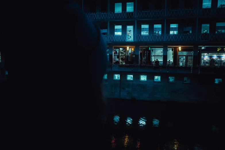 a building with some windows at night reflecting it in a body of water