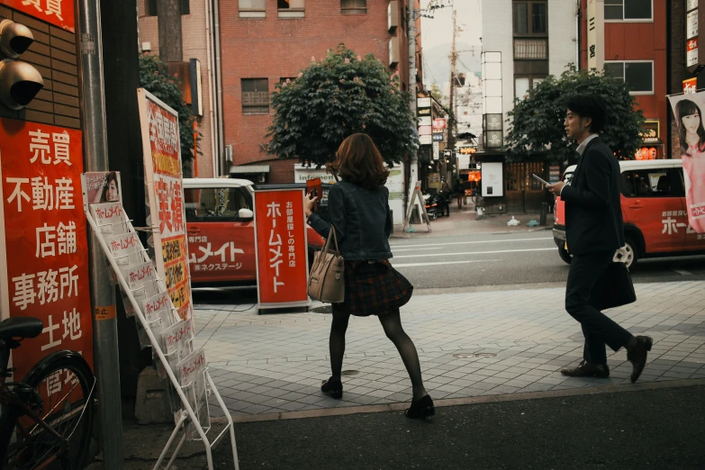 an asian man and woman are walking by the sidewalk