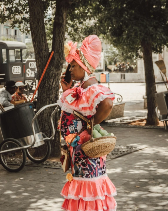 an african woman dressed in dress and accessories walking down the street on her cellphone