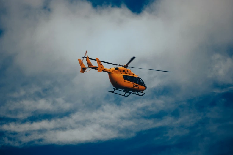 a helicopter in the air with clouds behind it