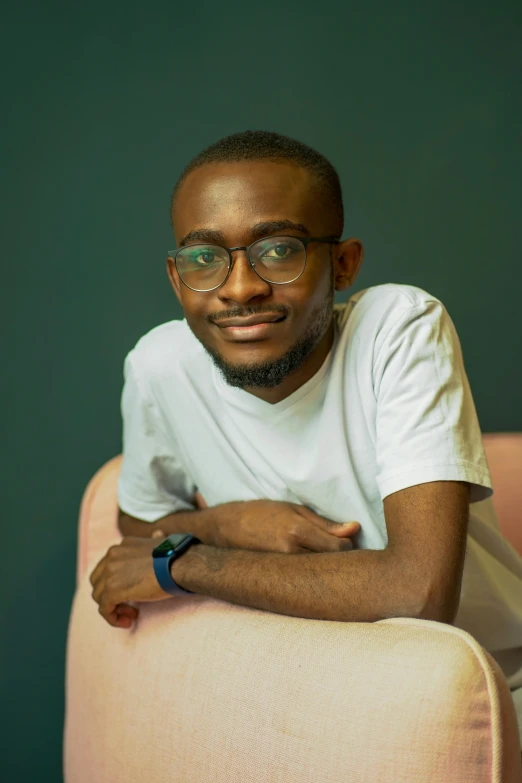 a man with glasses is sitting down and smiling