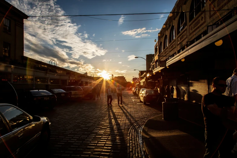 people walk down an old cobbled street at sunset