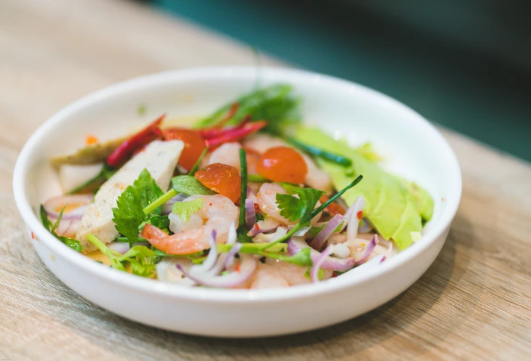 a white bowl filled with salads with lettuce and tomatoes